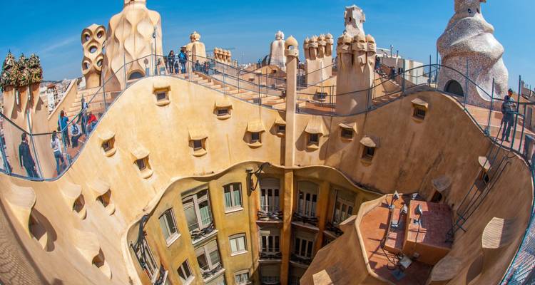 Vue en œil de poisson du toit de la Casa Milà de Gaudí avec des cheminées surréalistes et des visiteurs marchant le long de balcons courbes à Barcelone.