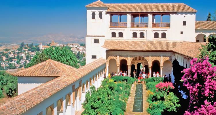 Bezoekers slenteren door de zuienengalerij van het Generalife-plein met fonteinen en uitzicht op de stad Granada.
