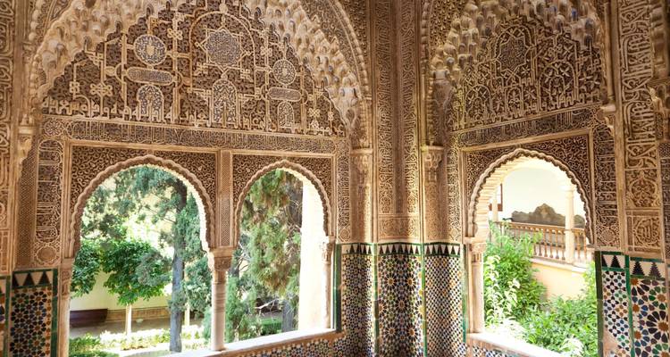 Ingewikkeld uitgesneden stucco bogen en kleurrijke tegelwerk in het Alhambra.