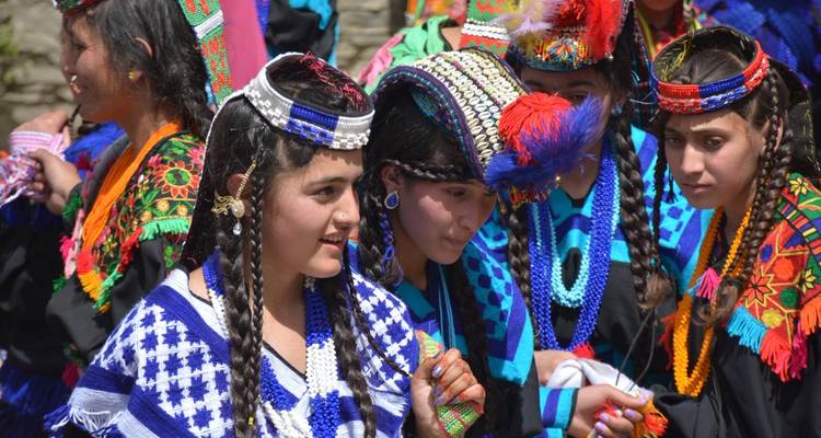 Kalash-Mädchen in leuchtenden traditionellen Kostümen und Perlenarbeiten während eines Kulturfestivals in Chitral.