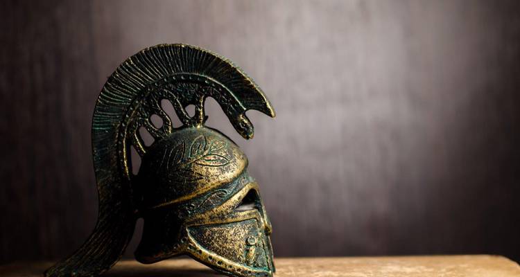 Artistieke close-up van antieke bronzen Spartaanse helm getoond tegen donkere achtergrond