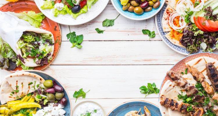 Gevarieerde Griekse gerechten en salades op een rustieke witte houten tafel uitgestald