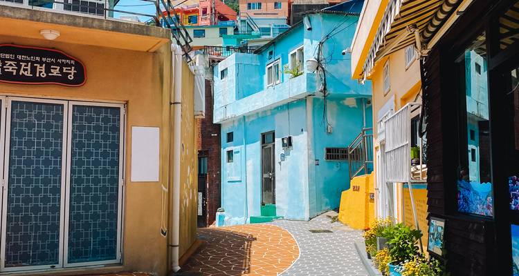 Ruelle étroite avec des maisons peintes de couleurs vives et un pavage à motifs dans un quartier situé sur les pentes d'une colline coréenne.