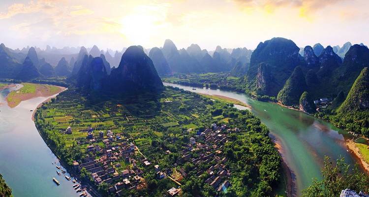 Vue panoramique aérienne des montagnes karstiques, de la rivière sinueuse et des terres agricoles baignées par la lumière de l'aube près de Guilin.