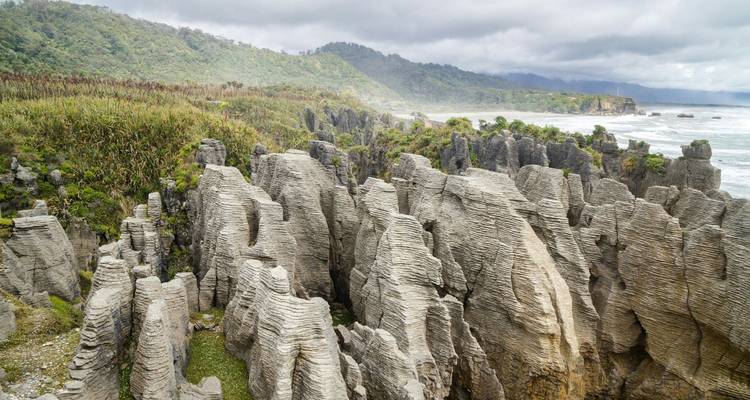 Formations rocheuses calcaires spectaculaires et en couches le long d'une côte accidentée sous un ciel nuageux