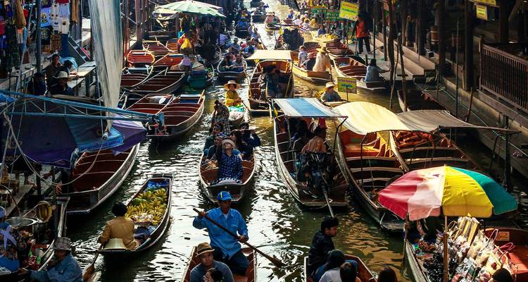 Marché flottant bondé avec des bateaux colorés vendant des marchandises le long d'un étroit canal