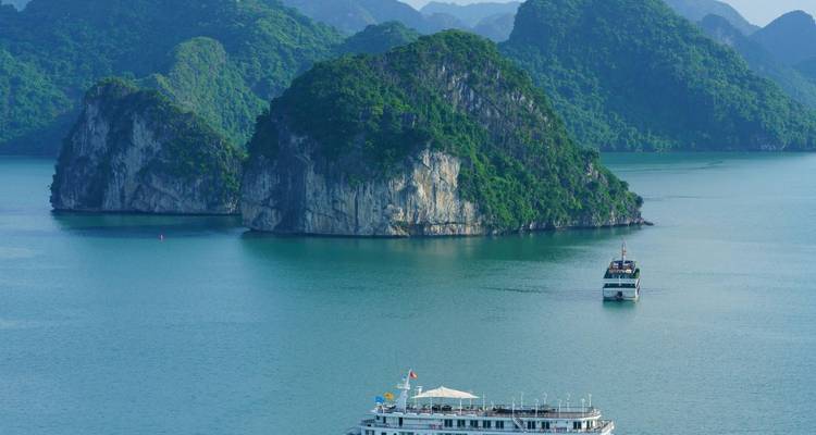 Navire de croisière naviguant dans les eaux turquoise parmi les îles karstiques