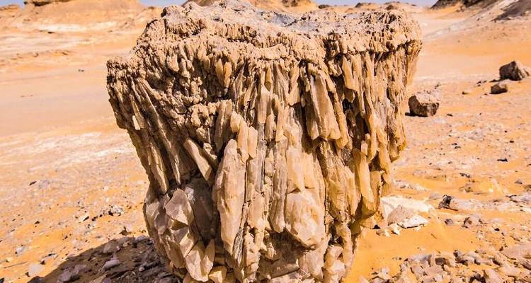 Primer plano de una formación de roca de cristal de cuarzo dramática en arena naranja