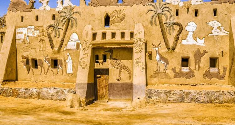 Edificio cubierto de barro decorado con relieves de animales y palmeras en un pueblo del desierto