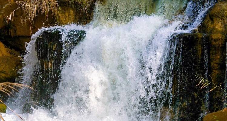 Kleine trapsgewijze woestijnwaterval omgeven door mosachtige rotsen