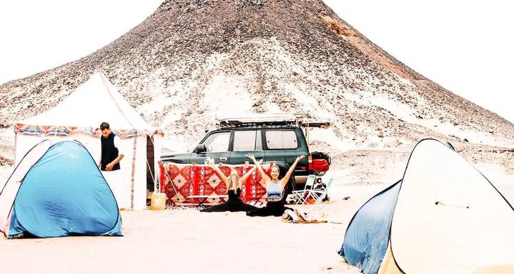 Campingszene mit zwei kleinen Zelten, 4x4-Fahrzeug und schwarzem Vulkanhügel im Hintergrund