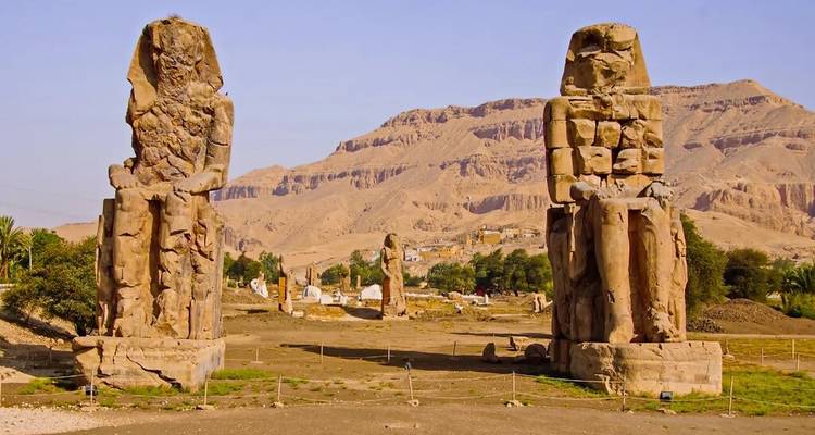 Las estatuas de los Colosos de Memnón se alzan imponentes frente a colinas áridas cerca de Luxor.