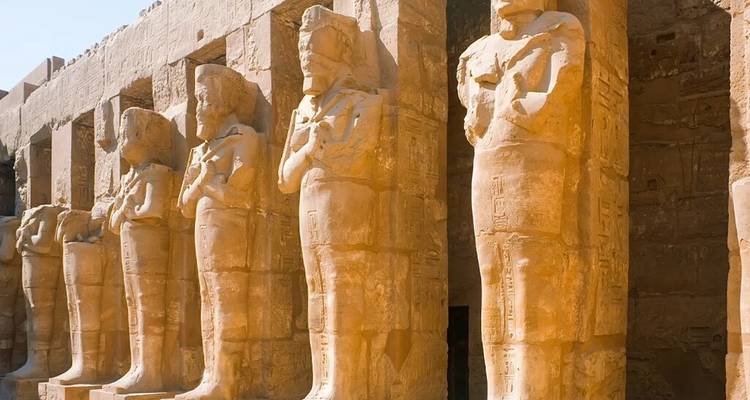 Fila de estatuas con cabeza de carnero bañadas en la cálida luz del sol en el complejo del Templo de Karnak.