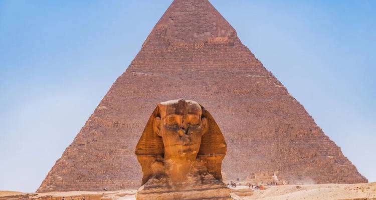 Vue de face du Sphinx avec la Grande Pyramide s'élevant directement derrière en pleine lumière du jour.