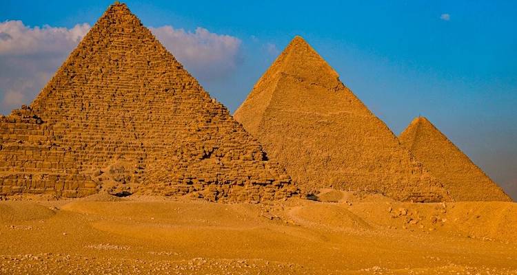 Drie grote piramides van Giza die in de woestijn staan onder een heldere blauwe hemel.
