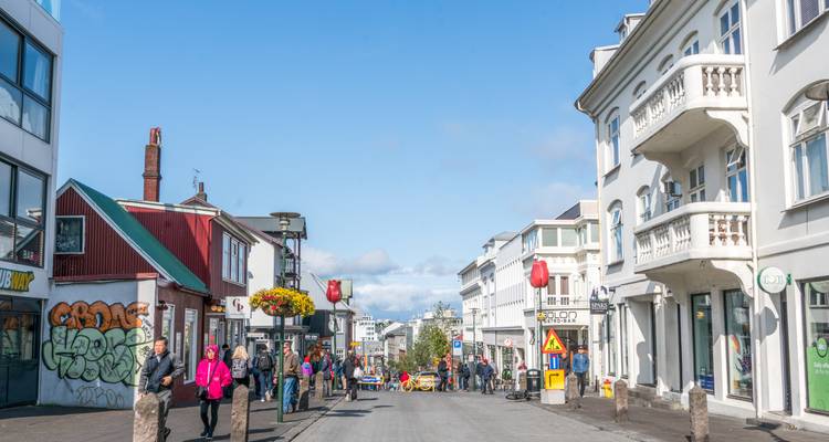 Rue piétonne animée à Reykjavik bordée de boutiques et de bâtiments colorés par une belle journée.