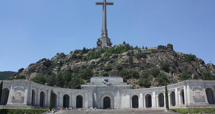 Una enorme cruz corona una colina rocosa sobre los arcos monumentales del memorial del Valle de los Caídos