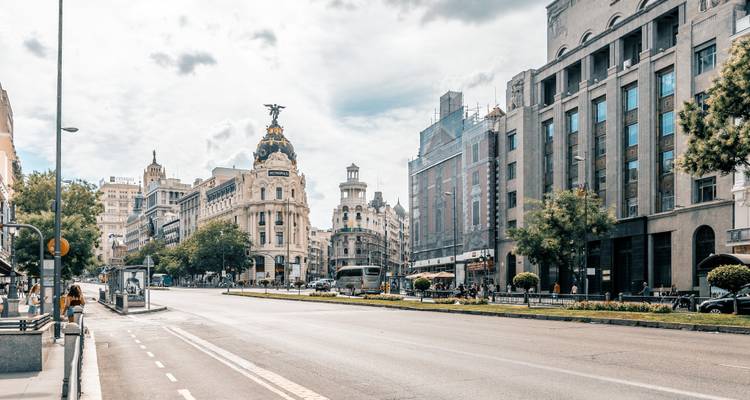 Amplia avenida Gran Vía con el edificio Metropolis y poco tráfico vehicular en una tarde nublada