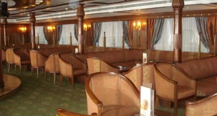 Warm verlichte cruisebar met rijen comfortabele stoelen en gordijnen voor de ramen.