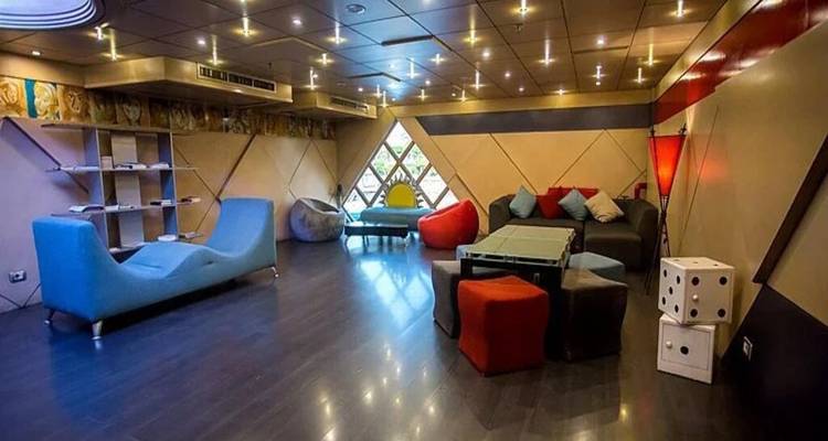 Salón moderno con muebles excéntricos, paredes geométricas y luces suaves en el techo.