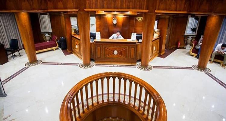 Zona de recepción amplia con pisos pulidos, pilares de madera y una escalera de gran envergadura.