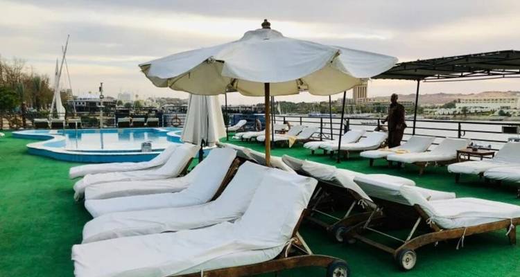 Leeg zonnedek met witte parasols en een klein zwembad met uitzicht op een rustige rivier op een cruiseschip