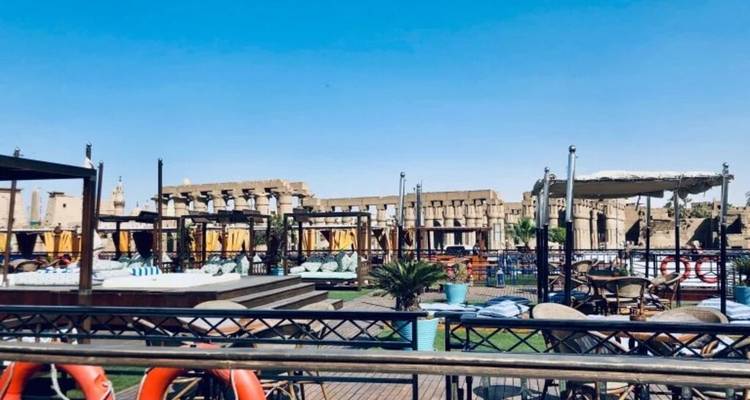 Zonnedek van een cruiseschip met cabana's en uitzicht op de oude stenen zuilen van de Karnak-tempel aan de overkant van de Nijl