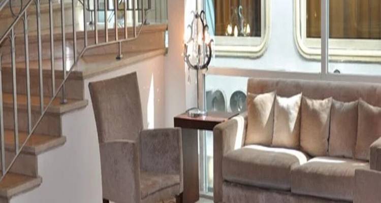 Zithoek met bank dicht bij een trap en groot raam in de lobby van een cruiseschip
