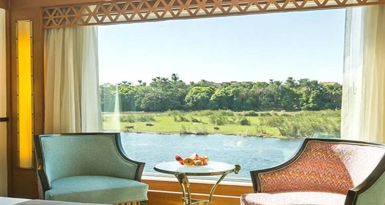 Twee stijlvolle fauteuils bij een groot panoramisch raam met uitzicht op weelderige oevers van de rivier