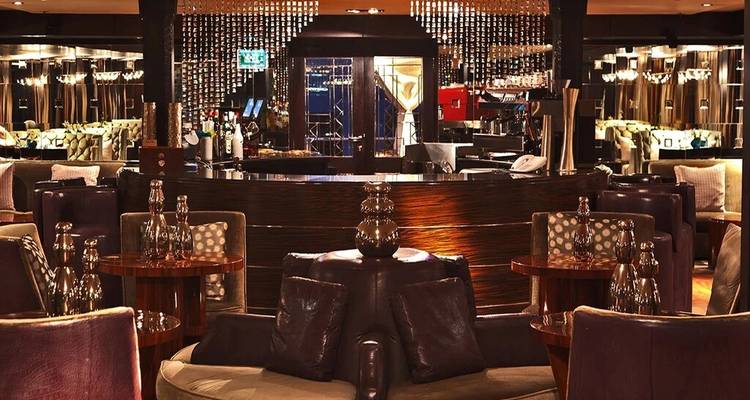 Bar lounge haut de gamme à éclairage tamisé avec sièges en cuir et lustres à perles scintillantes