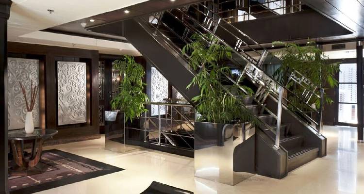 Hall d'accueil moderne de navire avec escalier chromé, panneaux de verre et plantes d'intérieur