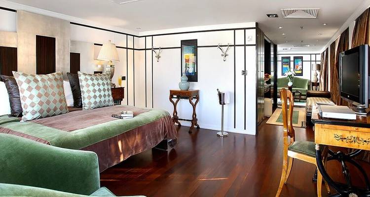 Suite spacieuse avec parquets en bois poli, mobilier en velours vert et décoration contemporaine