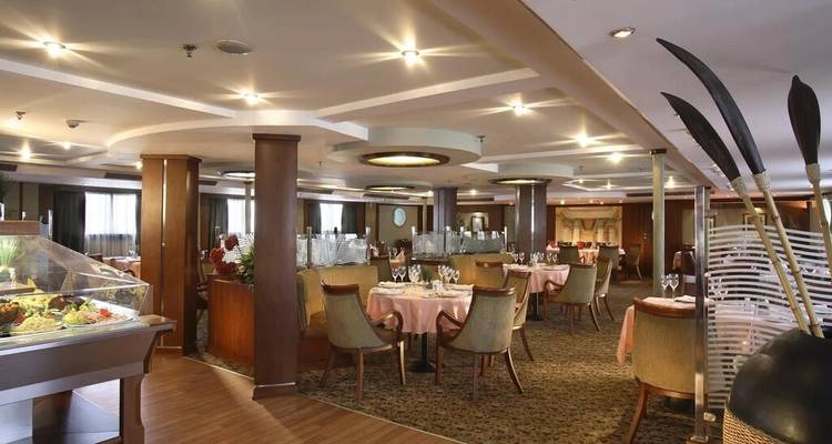 Elegant cruiseschip eetzaal met netjes gedekte tafels en warm omgevingslicht.