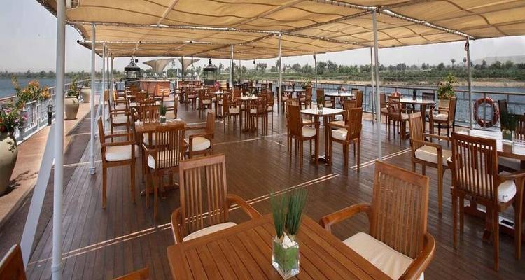 Restaurant met open terras van teakhouten dek op een cruiseschip met uitzicht op de Nijl en de omliggende platteland.