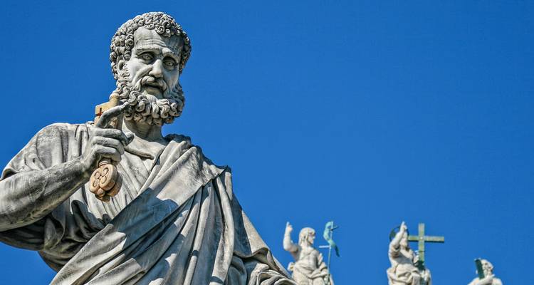 Statue des Heiligen Petrus vor tiefblauem Himmel mit Heiligen und Kreuzen im Hintergrund