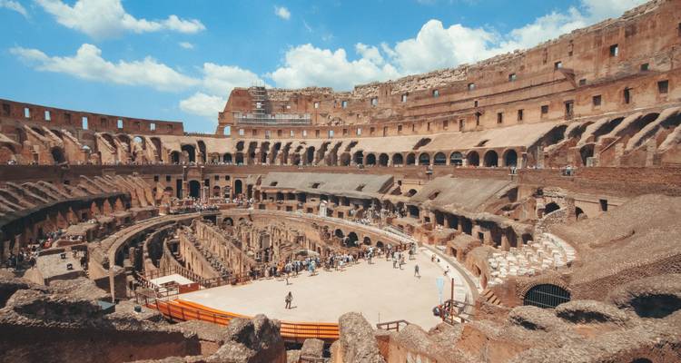 Innere Panoramaansicht des Kolosseums mit Touristen, die die antike Arena unter blauem Himmel erkunden.