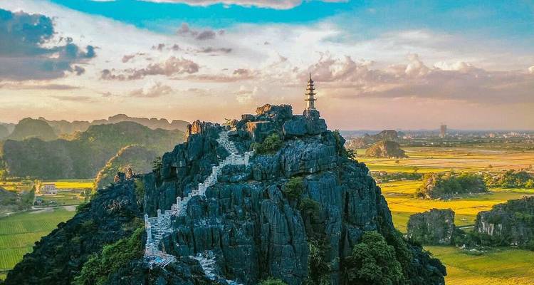 Vista aérea del Pico Hang Mua con escaleras en zigzag que conducen a una pagoda con vistas a los arrozales al atardecer.