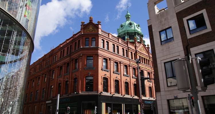 Bâtiment historique de grand magasin en briques rouges sous un dôme en cuivre dans une rue centrale de Dublin