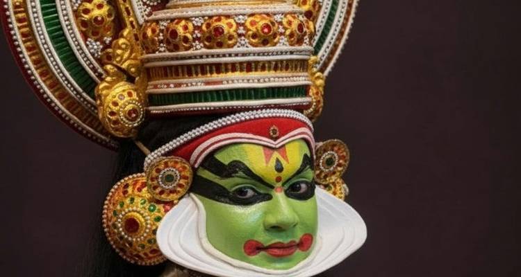 Intérprete de Kathakali elaboradamente disfrazado con maquillaje facial verde vívido y un tocado ornamentado contra un fondo oscuro