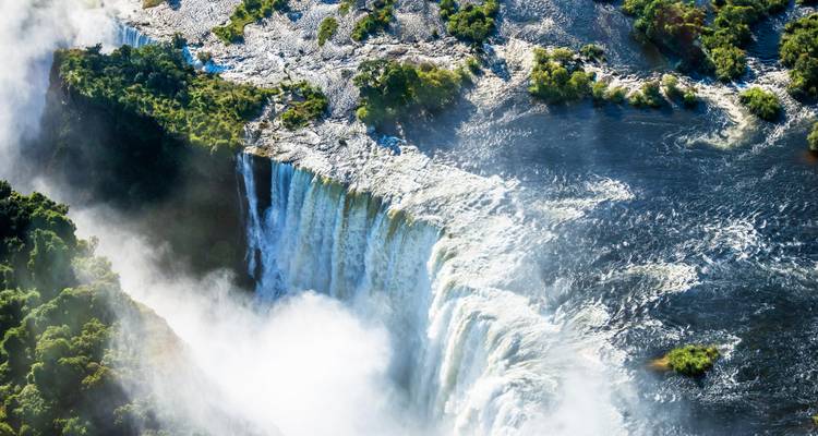 Vue aérienne des chutes Victoria avec la brume s'élevant du Zambezi qui se précipite.