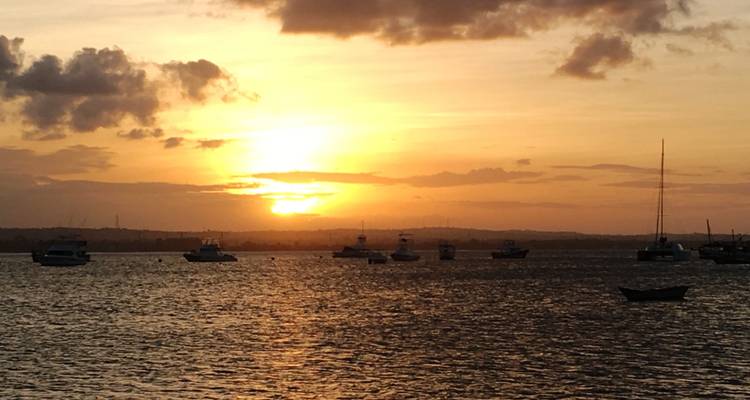 Atardecer tranquilo sobre un puerto con barcos anclados recortados contra un cielo naranja.