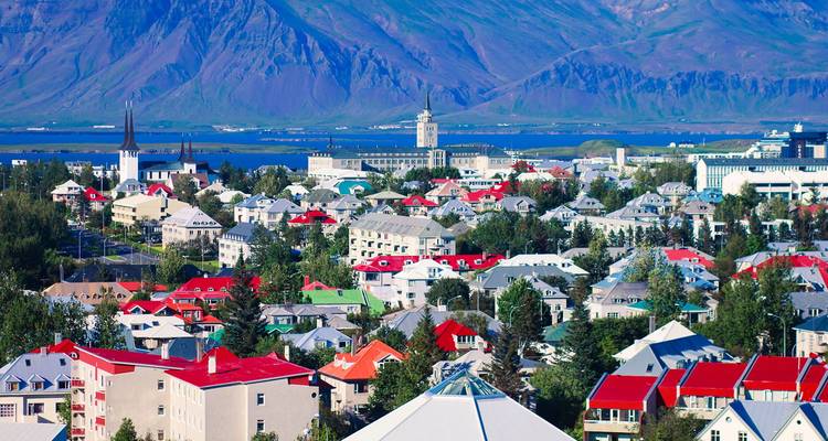 Vue aérienne colorée de Reykjavik avec des maisons aux toits rouges, des clochers d'église et des montagnes de l'autre côté de la baie.
