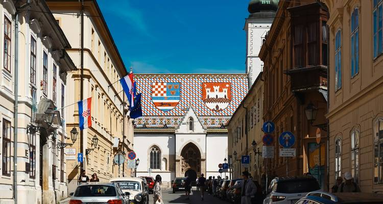 Straßenansicht in Richtung der Zagreber Markuskirche mit ihrem farbenfrohen Ziegeldach unter blauem Himmel
