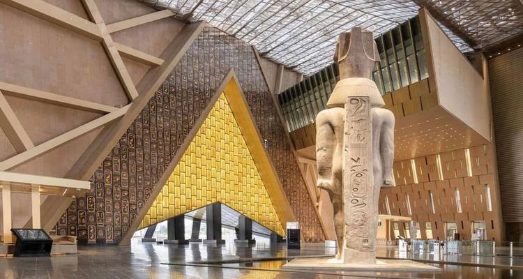 Foyer des Grand Egyptian Museum mit monumentaler Statue und gemusterter goldener Wand.