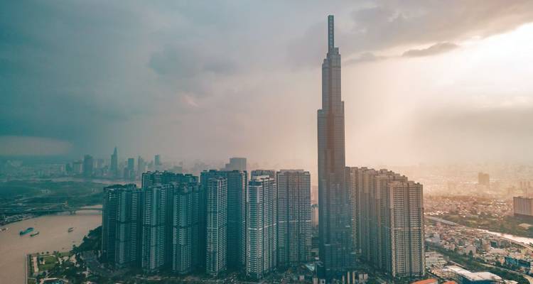 Luftaufnahme der Skyline von Ho-Chi-Minh-Stadt, dominiert von Landmark 81 und Clustern von Hochhäusern neben dem Saigon-Fluss bei nebligem Sonnenuntergang