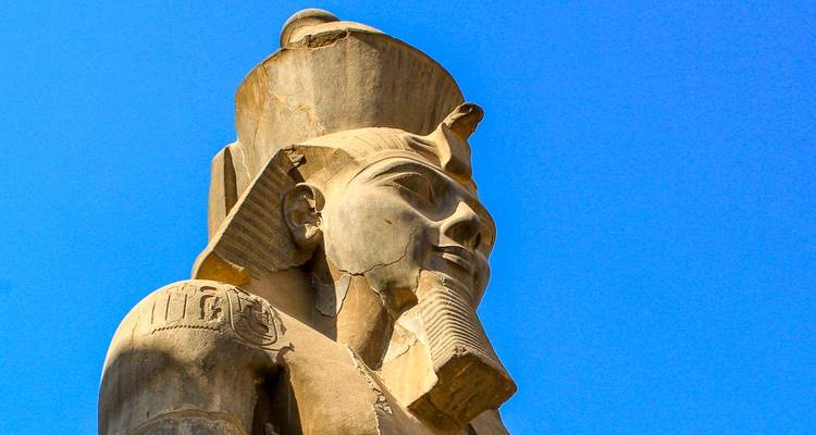 Majestica estatua del antiguo Egipto bajo la luz del sol domina un vibrante cielo azul de fondo.