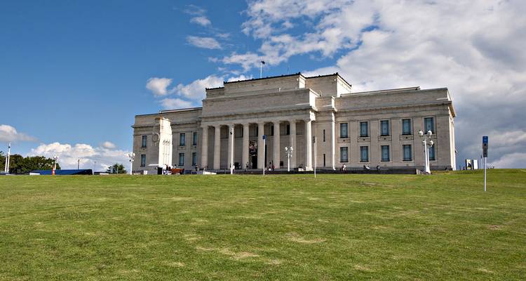 Edificio de museo neoclásico ubicado en un prado verde con un cielo azul de fondo