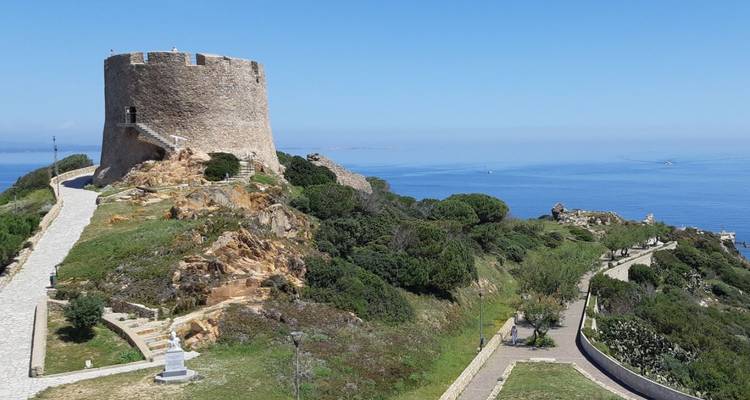 Tour de guet côtière en pierre perchée sur une colline rocheuse surplombant une mer calme