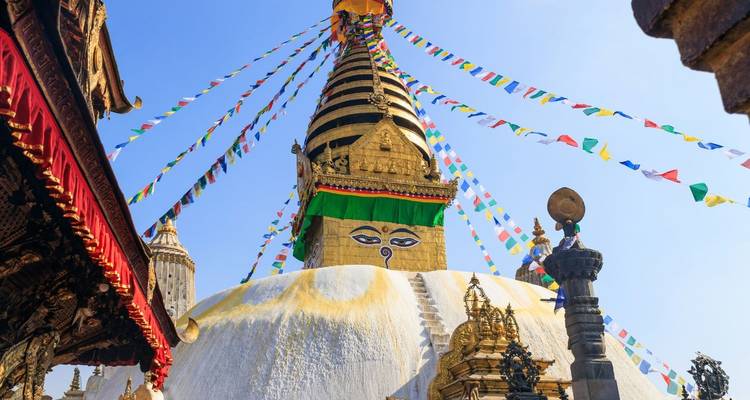 La dorada aguja de la estupa Swayambhunath con banderas de oración coloridas contra un cielo despejado
