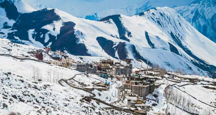 Pueblo de gran altitud cubierto de nieve con colinas volcánicas escarpadas en el Himalaya